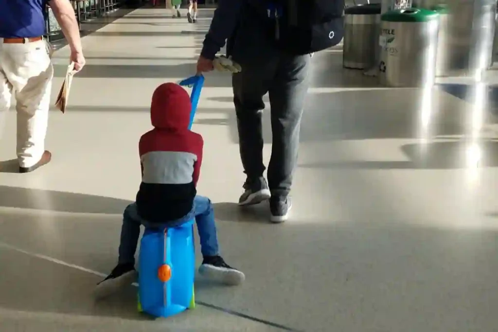 Parents and toddlers using colorful ride-on suitcases in airport