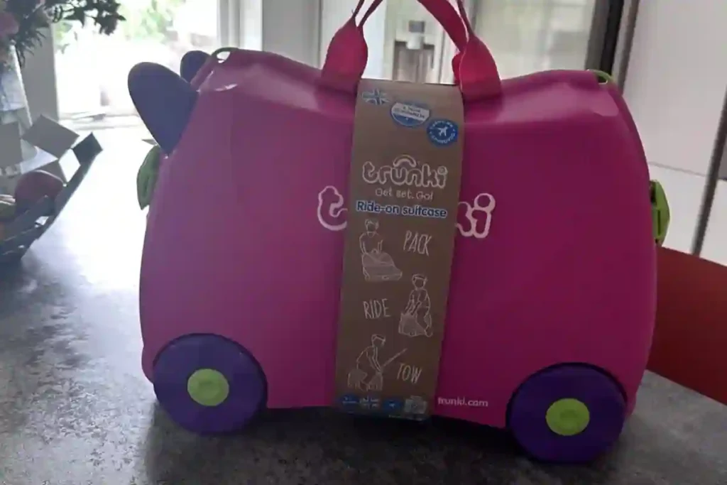 Toddler riding a Trunki suitcase with colorful playful design